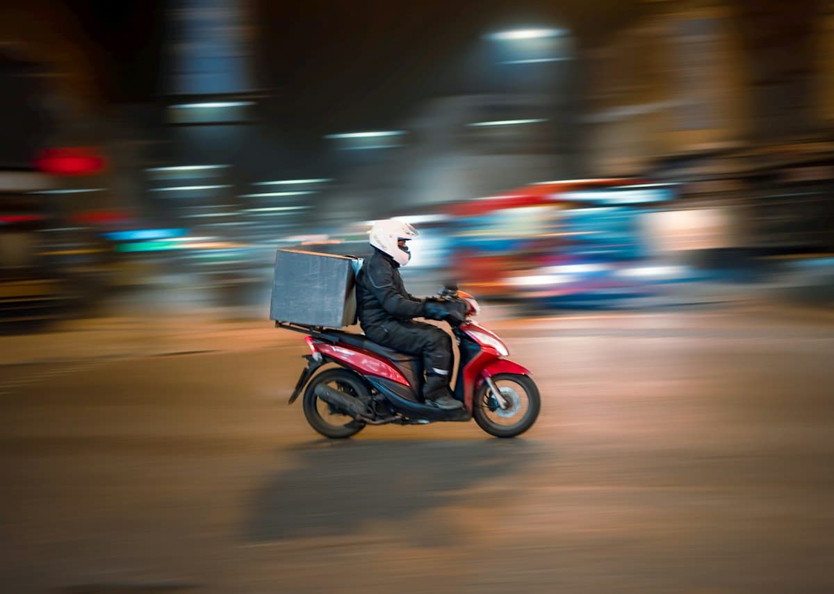 Delivery rider on a scooter at night, for quick delivery app development